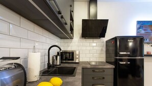 Une cuisine moderne avec un réfrigérateur noir, des appareils en acier inoxydable et un pare-feu en carreaux.