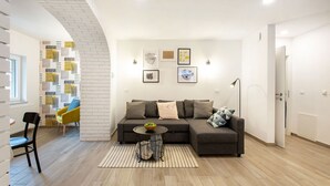 Un salon moderne avec un canapé d’angle, une petite table ronde et un tapis à motifs.