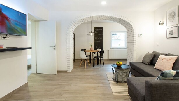 Un salon moderne comprenant un canapé, un téléviseur, un coin repas avec des chaises et un comptoir de cuisine.