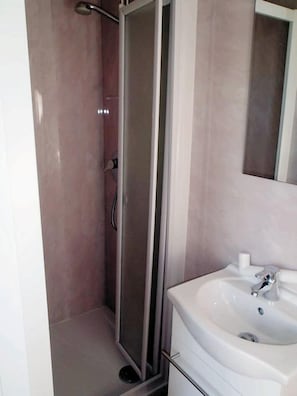 A bathroom with a shower enclosure, a sink, and a mirror. - Victoria Mobilehome Camping Ville Degli Ulivi (Campo nell'Elba)