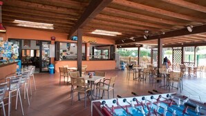 A spacious indoor area with wooden beams, tables, chairs, and a foosball table. - Victoria Mobilehome Camping Ville Degli Ulivi (Campo nell'Elba)