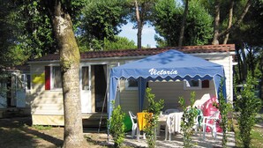 A small, single-story mobile home with a blue awning labeled "Victoria." - Victoria Mobilehome Camping Ville Degli Ulivi (Campo nell'Elba)