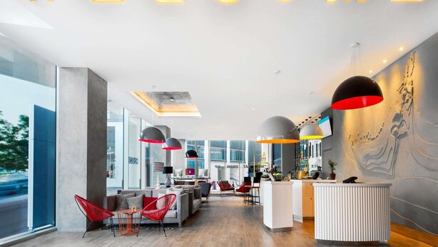 A modern reception area with a 'WELCOME' sign, seating, a reception desk, and large windows. - ibis Styles Dubai Airport Hotel (Dubai)