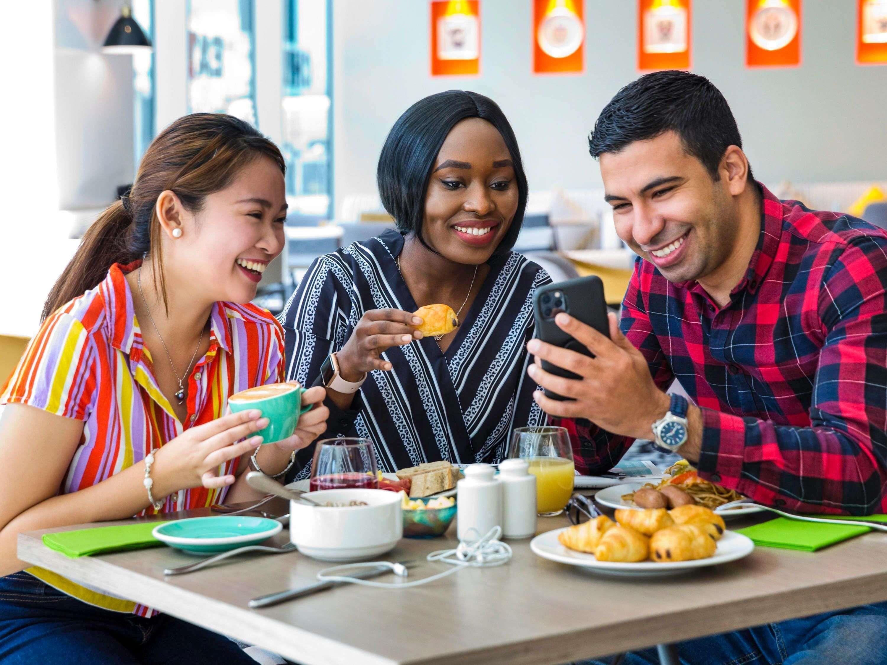 Trois personnes sont assises à une table, devant un petit-déjeuner composé de croissants et de jus de fruits.