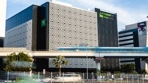 A modern hotel with a distinctive perforated facade, a prominent sign for 'ibis Styles Hotel', and a covered walkway. - ibis Styles Dubai Airport Hotel (Dubai)