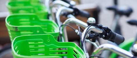 A row of bicycles with green baskets attached to the handlebars.