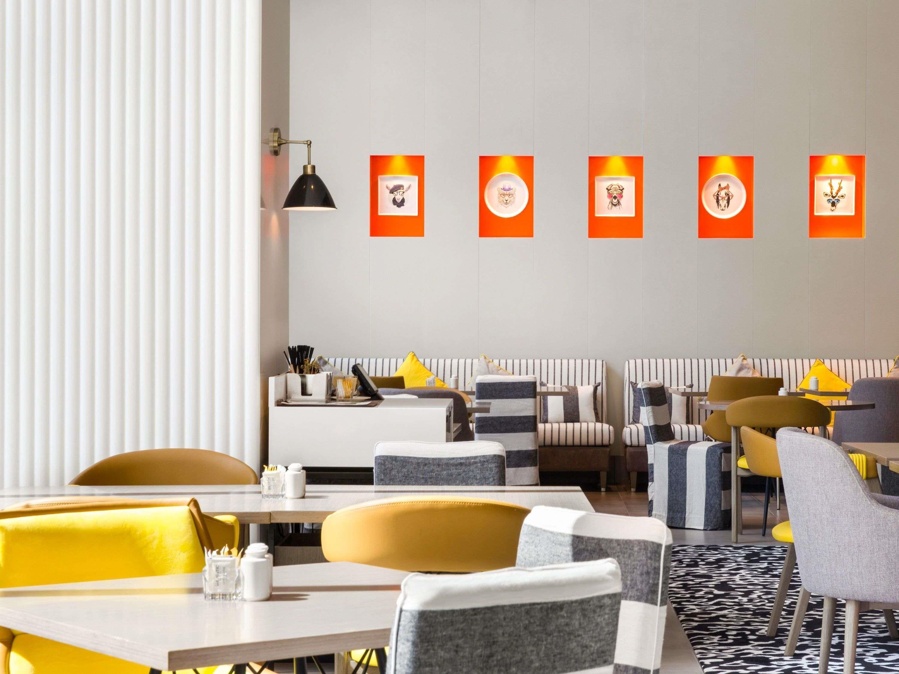 A modern dining area with striped booths, yellow and gray chairs, and a central table with condiments.