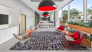 A modern living room with a large window, a black and red pendant light, and a view of the outdoors. - ibis Styles Dubai Airport Hotel (Dubai)