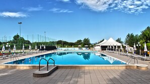 A large rectangular swimming pool with a tiled deck, surrounded by lounge chairs and umbrellas. - Victoria Mobilehome Stella del Sud Camping Villaggio (Rodi Garganico)