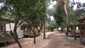 A row of wooden cabins with a gravel path between them. - Victoria Mobilehome Stella del Sud Camping Villaggio (Rodi Garganico)