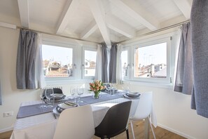 A dining area with a table set for four, large windows, and a view of buildings outside. - Venice Luxury Terrace View of San Marco (Venice)