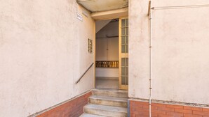 Una escalera estrecha que lleva a una habitación con suelo de baldosas y una puerta con picaporte de metal.