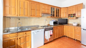 Una cocina con gabinetes de madera, un lavamanos de acero inoxidable, estufa, microondas y refrigerador.
