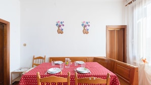Un comedor con mantel rojo, sillas de madera y una pequeña mesa con platos y cubiertos.
