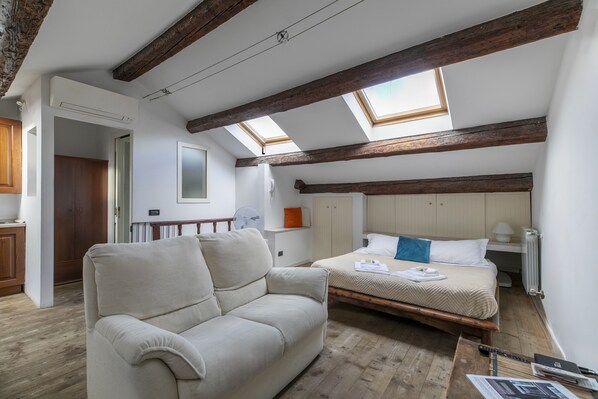 Ein Schlafzimmer mit Hochbett, Sofa, Holzboden und Dachfenstern.