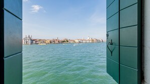 Visão através de uma porta verde de um corpo d'água com edifícios ao fundo.