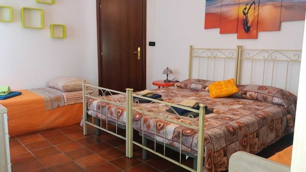 A bedroom with a bed, a smaller bed, a nightstand, a lamp, and a door. - Nice Apartment Venice (Mestre)
