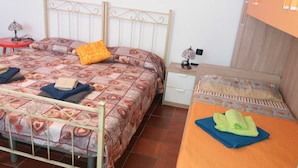 A bedroom with two beds, a nightstand, and a small table with a lamp. - Nice Apartment Venice (Mestre)