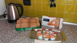 A kitchen counter with a box of biscotti, a tray of yogurt cups, and a kettle. - Nice Apartment Venice (Mestre)