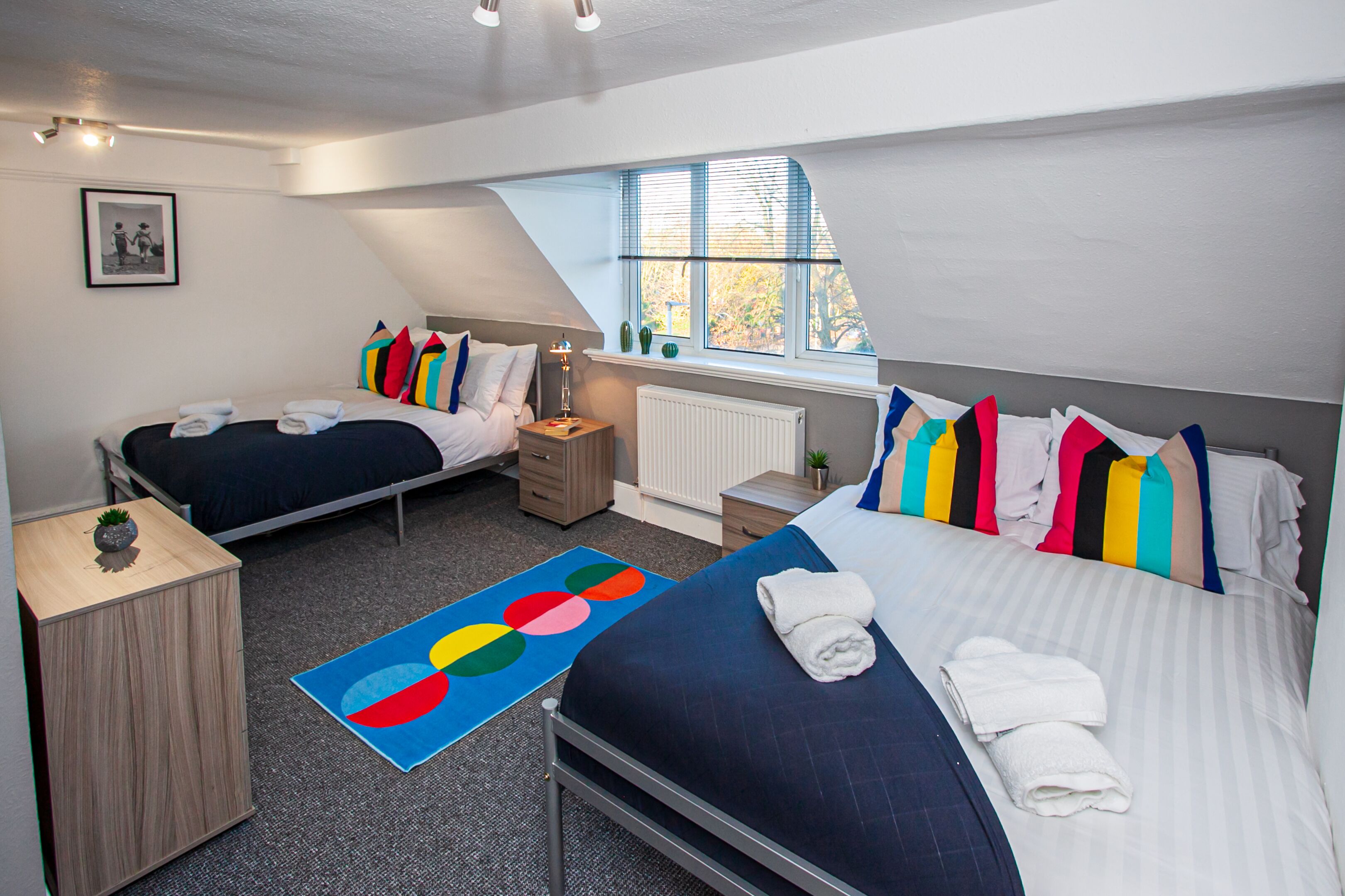Un dormitorio moderno con dos camas, un tragaluz y vistas al exterior.