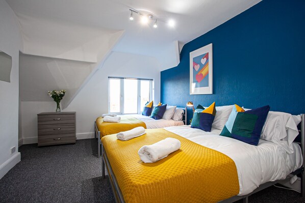 A hotel room with two beds, a dresser, and a large window. - The Manchester Pad - Sleeps 12 (Manchester)