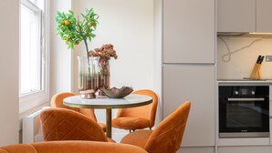 Een moderne keuken met witte kasten, een Bosch oven en een eethoek met oranje stoelen en een ronde tafel.