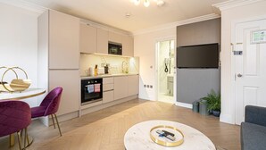 Een moderne keuken met witte kasten, een inbouwoven en een flatscreen televisie boven de aanrecht.