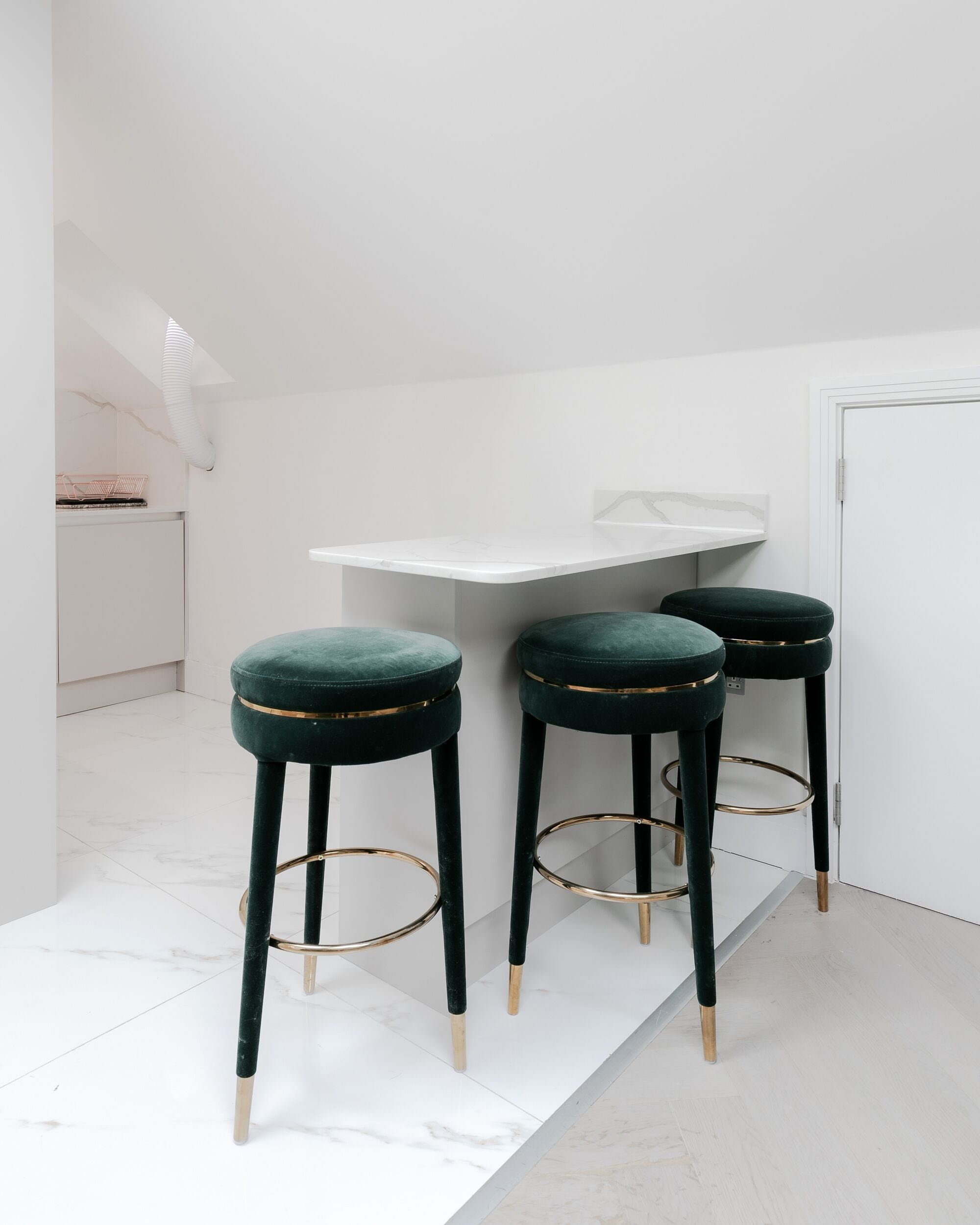Una cocina moderna con armarios blancos, una encimera blanca y una puerta blanca.