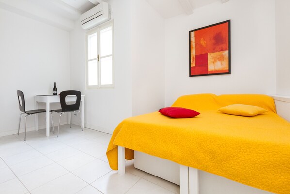 Relax in a cozy space with a comfortable bed, a stylish chair, and a beautiful abstract art piece.