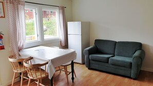 A small room with a table and chairs, a sofa, and a white refrigerator. - Hovstø (Seljord)