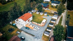 An aerial view of a residential area with a large house, several smaller houses, and a parking area. - Hovstø (Seljord)