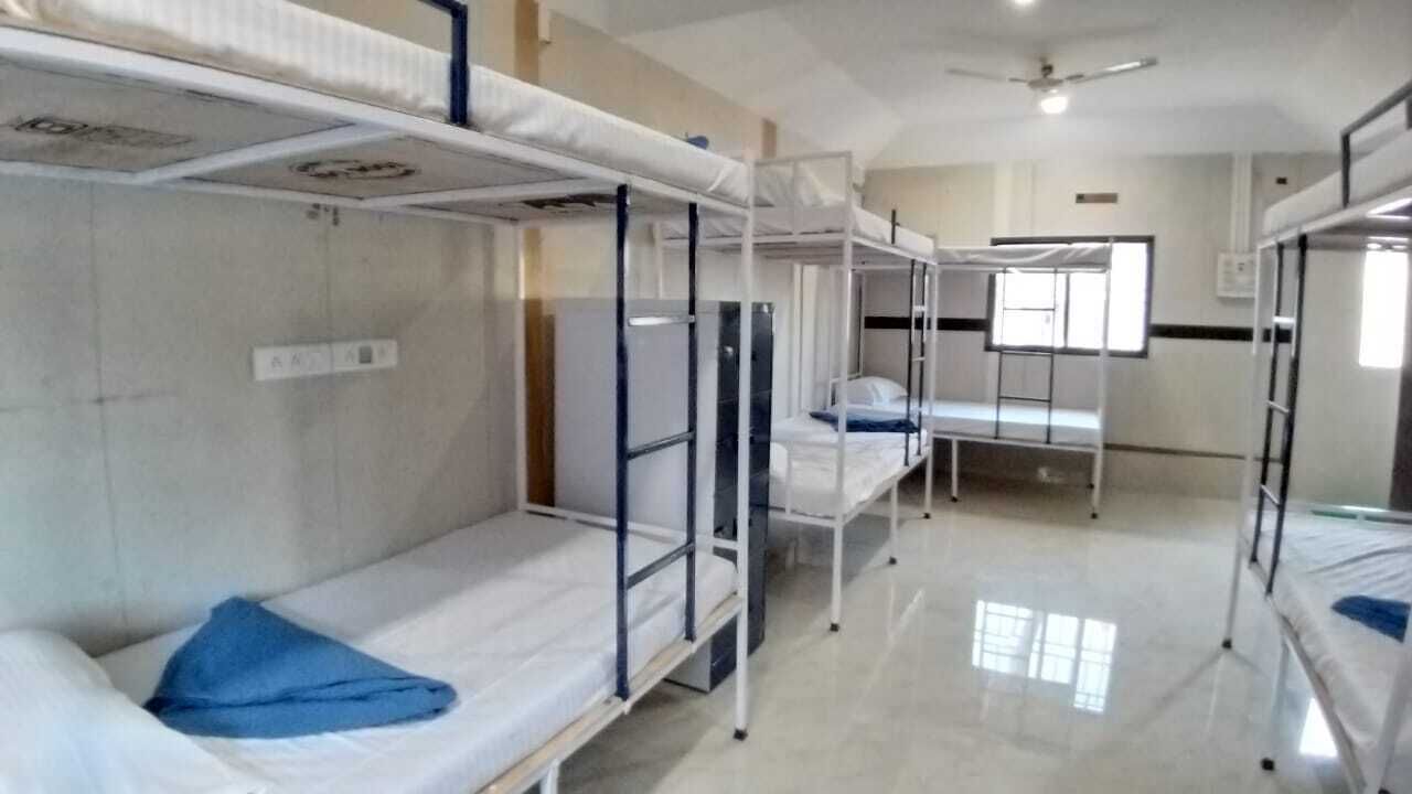 A dormitory room with bunk beds, a ceiling fan, and a window providing natural light.