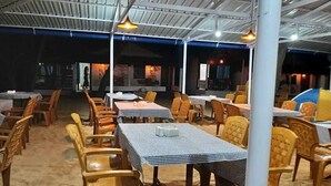 Un restaurante interior con varias mesas y sillas, cubierto por un techo metálico.