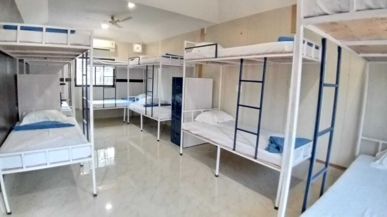 A dormitory room with bunk beds, a ceiling fan, and a window.