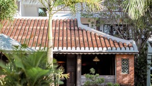 A traditional house with a tiled roof, a wooden porch, and a brick wall. - De An Hotel (Da Nang)