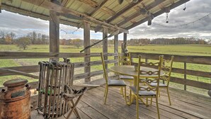 Un rústico espacio al aire libre con una mesa y sillas de madera, un farol de metal y una lámpara de aceite antigua.