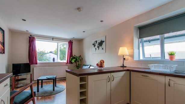 A compact kitchen with a dining area, a television, and a window with curtains. - 70 Elm Street (Cardiff)