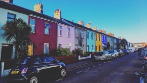 A row of colorful terraced houses with parked cars on the street. - 70 Elm Street (Cardiff)