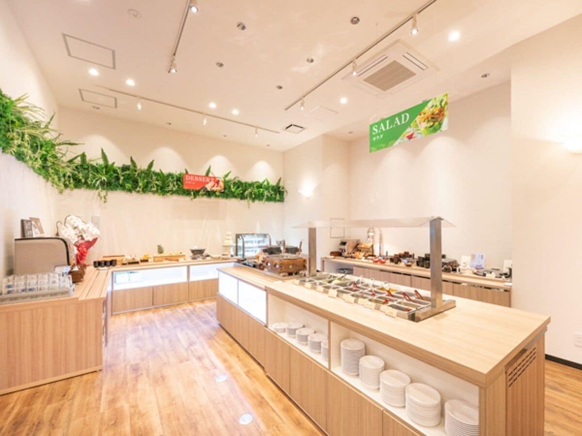 Een buffetgedeelte met meerdere aanzitpunten, een bord met salades en een toonbank met diverse gerechten.