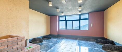 Una habitación con piso de baldosas, chimenea de ladrillo y un ventanal amplio.