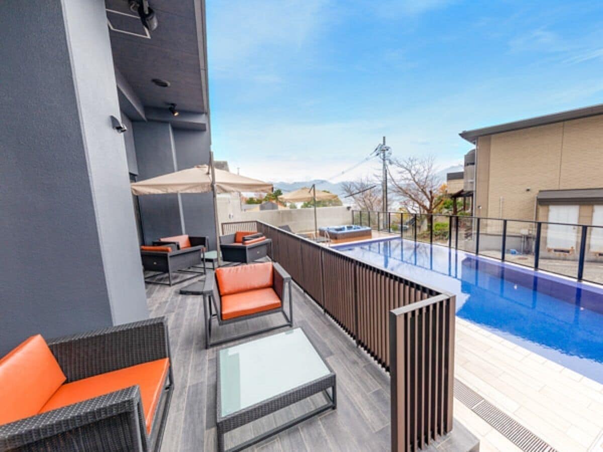 A rooftop terrace with outdoor seating, a swimming pool, and a view of the mountains.