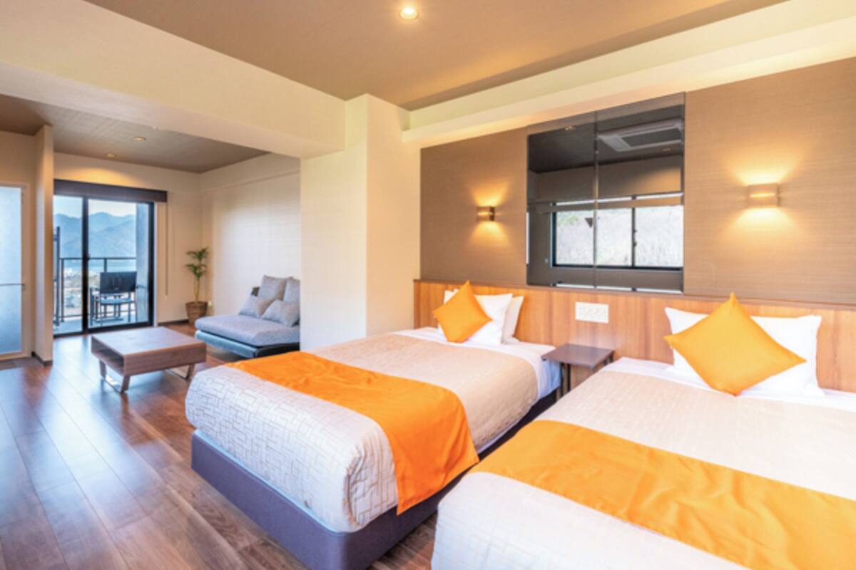 A hotel room with two beds, a balcony, and a view of the mountains.
