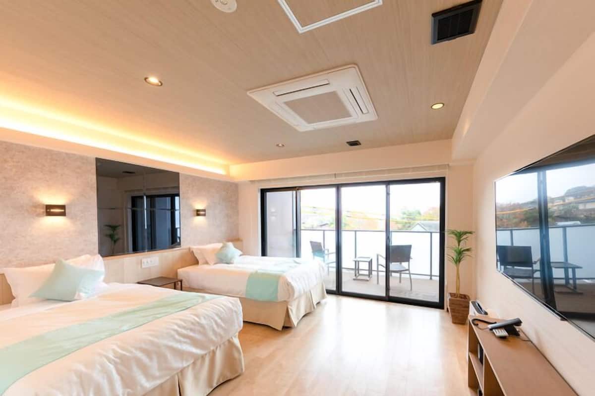 Une chambre d’hôtel moderne avec deux lits, un balcon et une grande fenêtre.