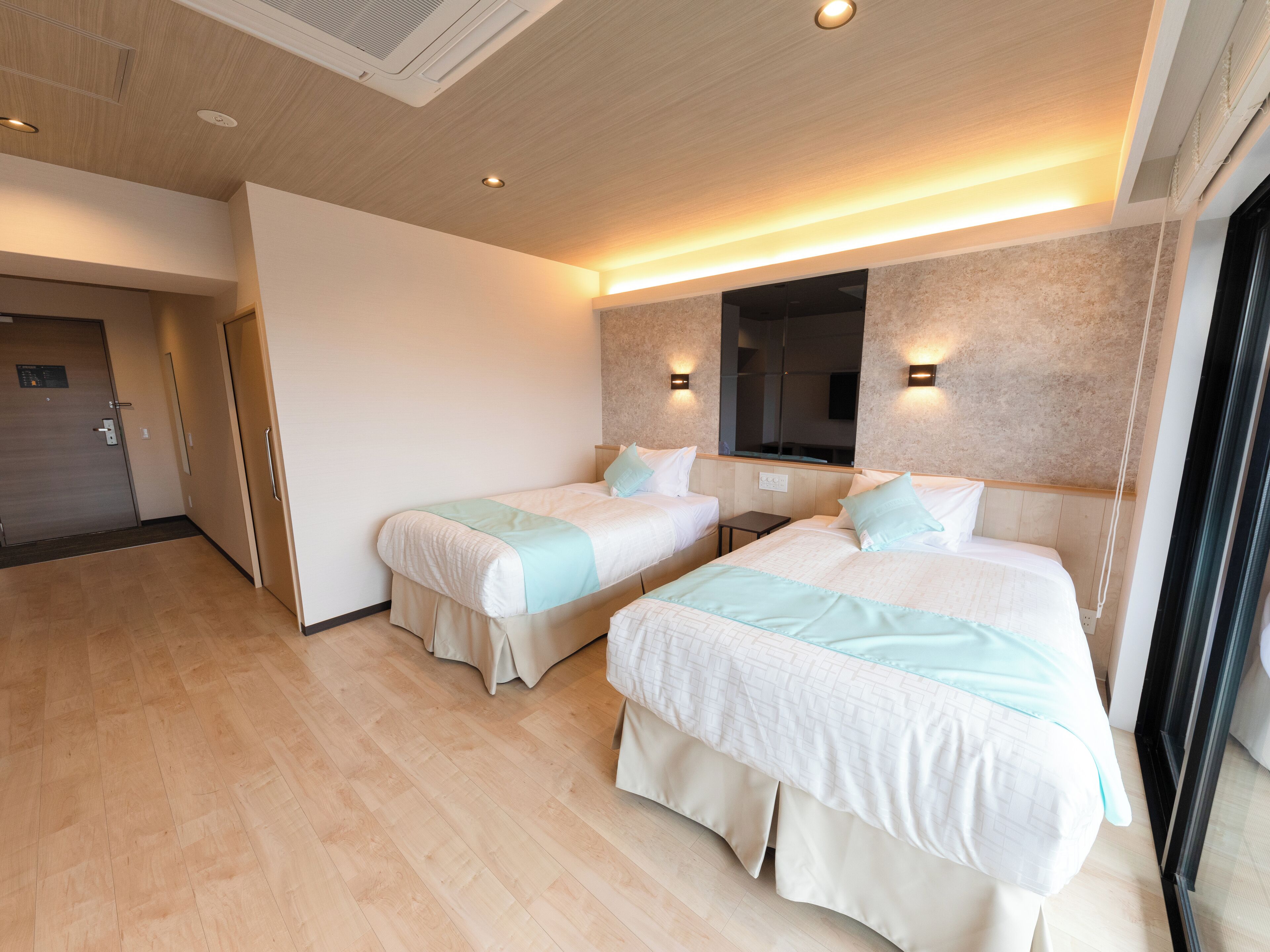 Una habitación de hotel moderna con dos camas, un espejo grande y piso de madera.