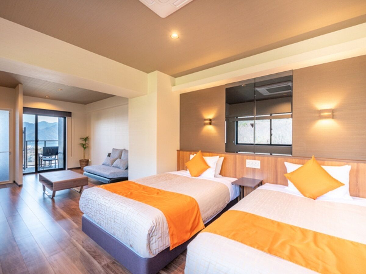 A hotel room with two beds, a balcony, and a view of the mountains.