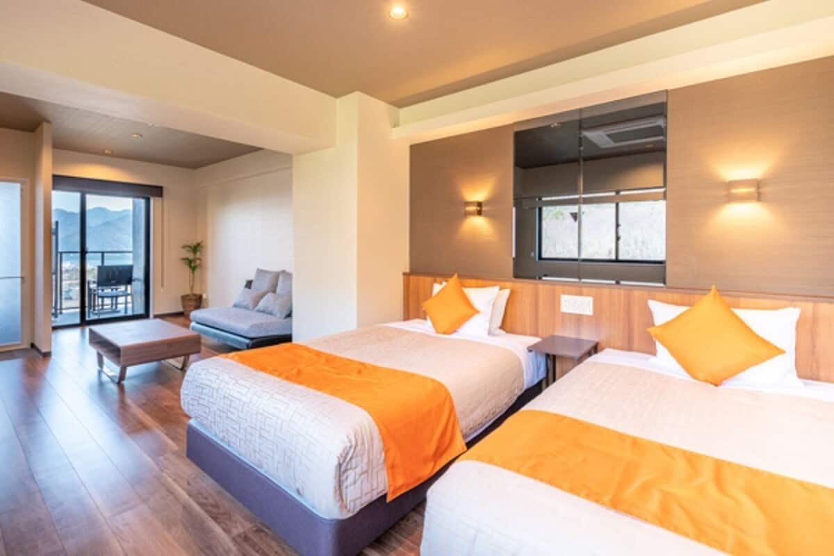 A hotel room with two beds, a balcony, and a view of the mountains.