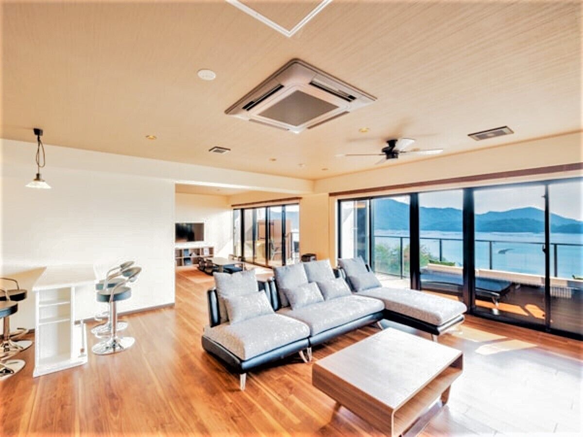 A spacious living area with a large sofa, a coffee table, and a view of the outdoors.