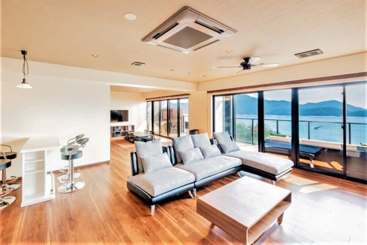 A spacious living area with a large sofa, a coffee table, and a view of the outdoors.