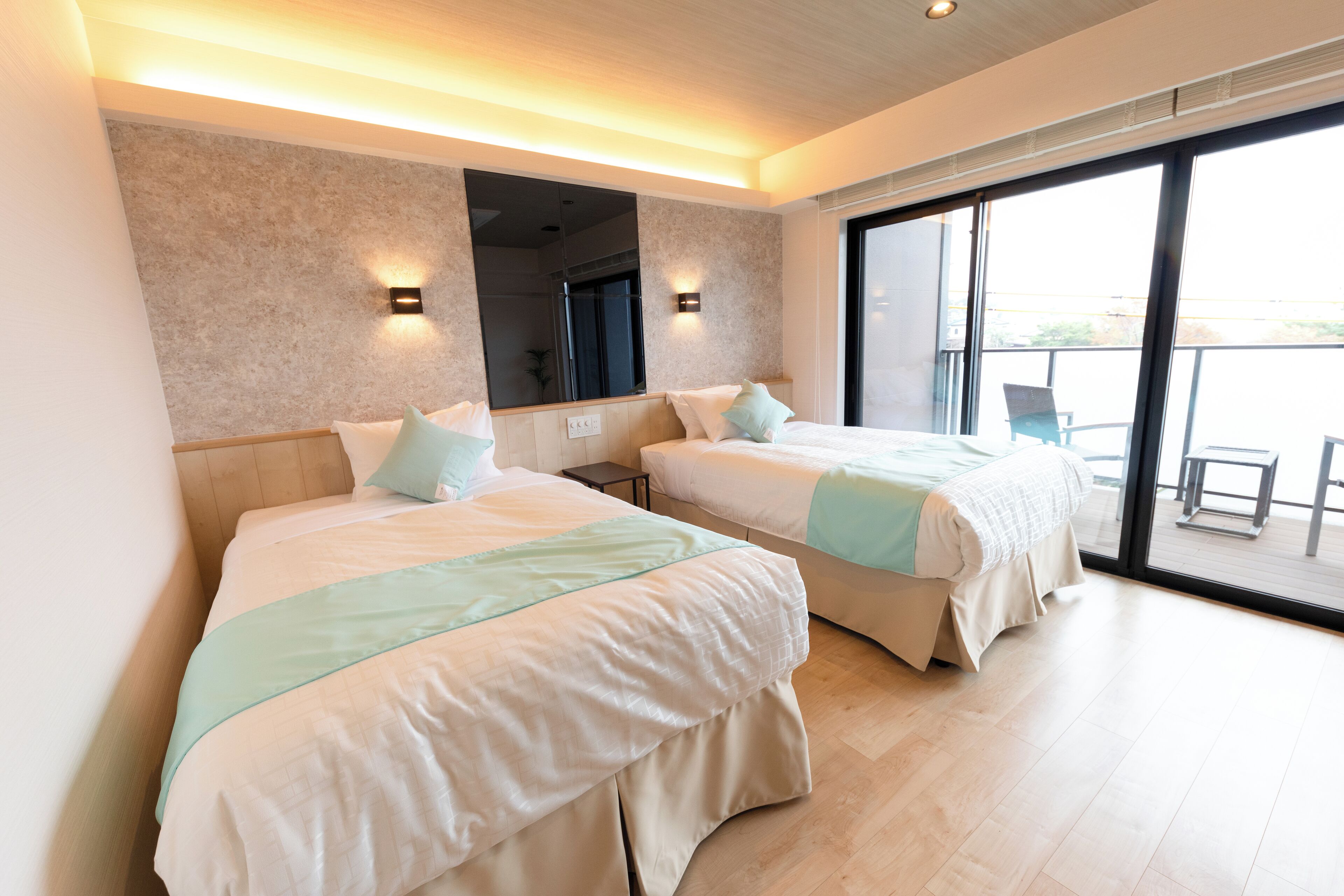 A hotel room with two beds, a large window, and a balcony.