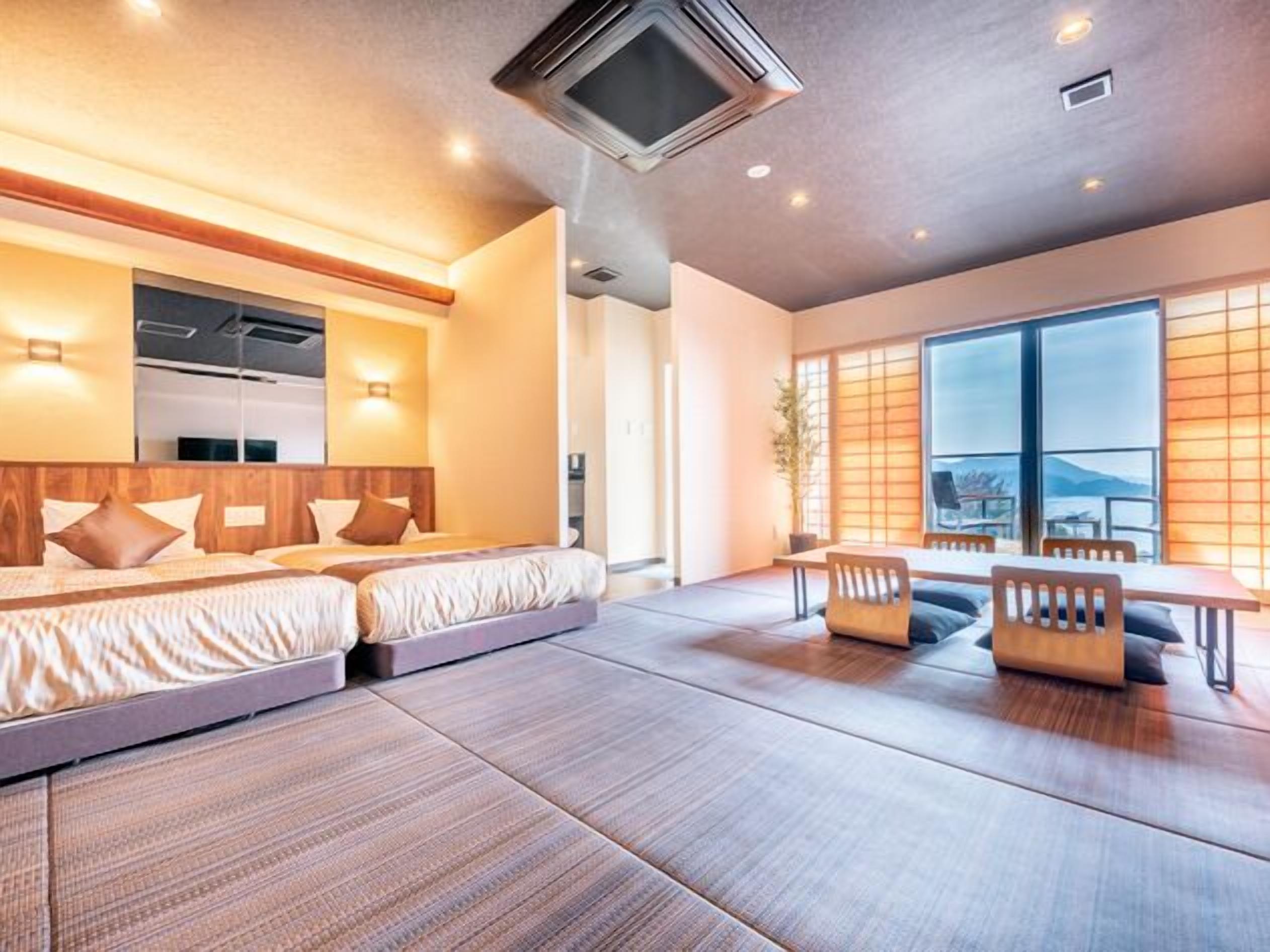 A modern hotel room with a large bed, a seating area with a table, and a view of the outdoors.